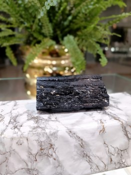 Dekoracyjna bryłka czarnego turmalinu o surowej strukturze na marmurowym bloku, minerał naturalny Brazi