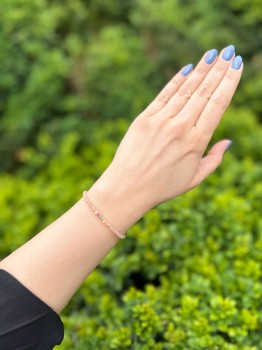 Bransoletka z naturalnych minerałów na dłoni na tle zielonych liści, ręcznie wykonana biżuteria Brazi