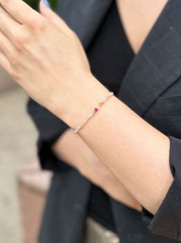 Bransoletka z różowym kamieniem i złotymi elementami na nadgarstku, ręcznie robiona biżuteria Brazi.