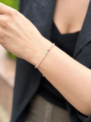 Kolorowa bransoletka z kamieni naturalnych przy rękawie czarnej marynarki, biżuteria Brazi.