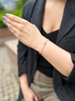 Bransoletka z minerałów z zapięciem zodiakalnym na nadgarstku modelki w czarnej marynarce, marka Brazi