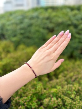 Bransoletka z drobnych kamieni fasetowanego granatu na nadgarstku modelki, biżuteria Brazi.