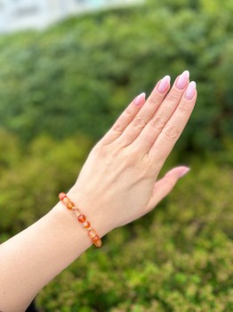 Bransoletka z fasetowanym karneolem na nadgarstku modelki, biżuteria Brazi na tle natury