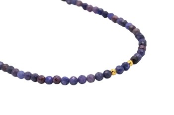 Zbliżenie na fasetowane koraliki naturalnego szafiru i złocone elementy dekoracyjne naszyjnika marki Brazi