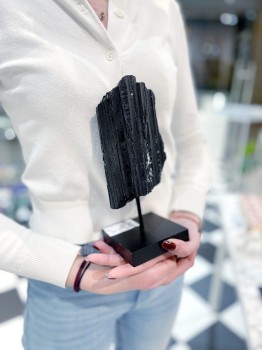 Czarny turmalin na podstawce trzymany w dłoniach, duży minerał dekoracyjny, marka Brazi.