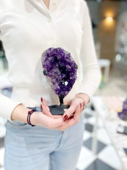 Naturalna szczotka ametystu na podstawce trzymana w dłoniach, prezentacja skali produktu Brazi