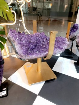 Boczny widok na bryłę surowego ametystu, dekoracyjny stolik kawowy ze złotą podstawą Brazi.