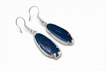 Kolczyki z naturalnym agatem w formie plastra ułożone na jasnym tle, biżuteria Brazi